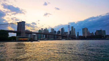 Brooklyn Köprüsü ve Manhattan ufuk çizgisi gün batımında. Arkasında Manhattan silueti olan Brooklyn Köprüsü 'nün güzel bir günbatımı manzarası.