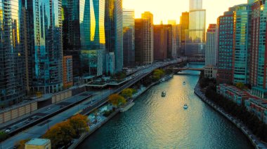 Chicago Illinois 17.10.2024. Günbatımında Yansıtıcı Gökdelenleri olan Chicago Nehri. Şikago Nehri 'nin gökdelenlerle çevrili havadan görünüşü ayının altın renklerini yansıtıyor.