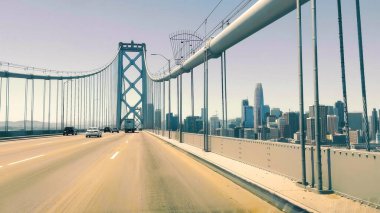 San Francisco Skyline ile Iconic Bay Köprüsü. San Francisco 'daki Bay Köprüsü' nün manzarası. Arabalar açık bir gökyüzünün altında ufuk çizgisine doğru ilerliyor.