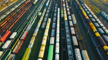 Renkli kargo konteynırlarıyla dolu tren istasyonunun havadan görüntüsü. Yoğun bir tren istasyonunun hava perspektifi, çeşitli renklerde kargo konteynırları ve yük vagonları sergileniyor.