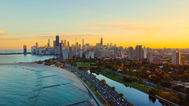 Chicago Skyline ve Michigan Gölü Sunset 'te. Gün batımında Michigan Gölü boyunca Chicago 'nun gökyüzü manzarası, plajlar, parklar ve sıcak akşam ışığı ile çevrili yoğun göl yolu.