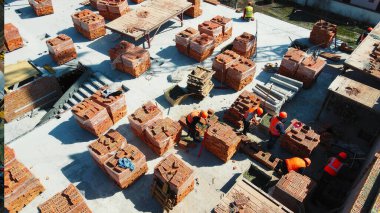 İnşaat alanında tuğla döşeme ve inşaat işçileri. İnşaat işçilerinin tuğla istifledikleri ve inşaat alanında çalıştıkları hava manzarası.