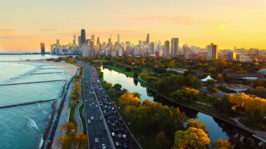 Lakefront View ile Sunset 'teki Chicago City manzarası. Gün batımında Chicago 'nun gökyüzü manzarası Michigan Gölü' nün kıyı şeridini, ağaçlarla kaplı parkları ve liman boyunca uzanan yoğun bir yolu gösteriyor.