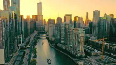 Chicago Illinois 17.10.2024. Chicago River Surrounded by Skyscrapers at Sunset. Aerial view of the Chicago River winding through downtown, surrounded by skyscrapers and illuminated by a golden sunset clipart