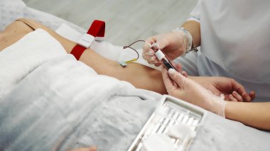 Hemşire hastadan kan örneği topluyor. Eldiven giyen ve şırınga kullanan bir hastanın kolundan nazikçe kan örneği alan bir sağlık uzmanının yakın plan fotoğrafı.
