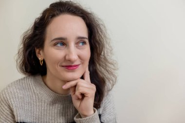 Gülümseyen bir kadın, düşünceli bir pozla çenesini elinin üzerinde dinlendirirken, gülümseyen bir kadın, düşünceli bir şekilde yan tarafa bakıyor. Metin için boşluk