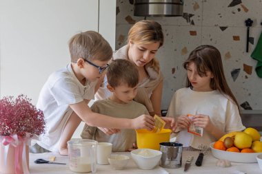 Anne ve çocuklar mutfakta birlikte yemek pişiriyorlar, evde çocuklarla birlikte aile yemekleri yapıyorlar.