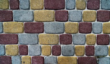 Kırmızı, sarı ve gri dikdörtgen tuğlaların yer aldığı karmaşık geometrik desenli çok renkli kaldırımlar görsel olarak çekici bir yüzey oluşturuyor.