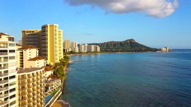 Waikiki Sahili 'nin ufuk çizgisi Diamond Head manzaralı. Waikiki Sahili manzaralı, yüksek binalı oteller, turkuaz okyanus suları ve berrak gökyüzünün altında Diamond Head krateri.
