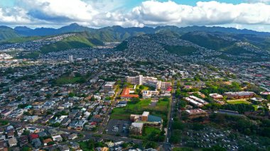 Honolulu Mahallesi ve Dağları 'nın havadan görünüşü. Honolulu, Hawaii 'deki yerleşim yerlerinin geniş hava manzarası, yemyeşil dağlar ve arka planda dağınık bulutlar.