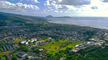 Doğu Honolulu ve sahil şeridinin hava görüntüsü. Yeşil tepeleri, kıyı yolları ve okyanus ufkunun dağınık tropikal bulutların altında olduğu Doğu Honolulu mahallelerinin hava manzarası.