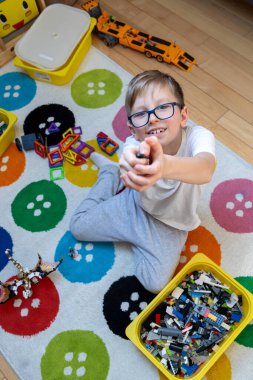 Evdeki renkli bloklarla oynayan mutlu çocuk. Gülümseyen çocuk renkli bloklar ve oyuncaklar ile yaratıcı oyunların keyfini çıkarıyor..