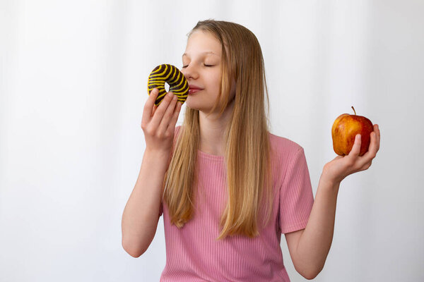 Teen Girl Choosing Between Donut and Apple. Teenage girl holding a striped donut and an apple, symbolizing healthy eating choices versus sugary temptation in daily diet