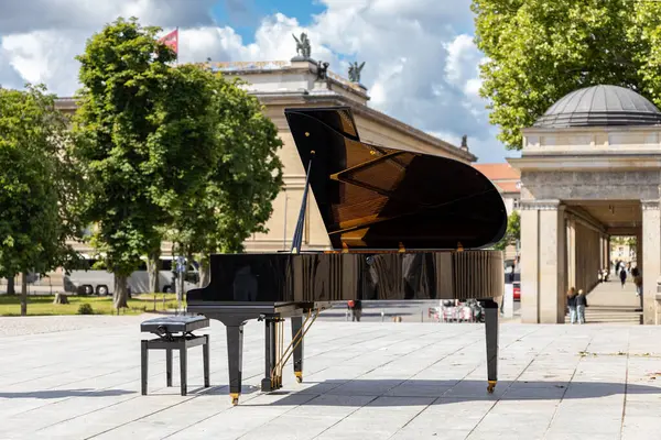 Tarihi Şehir Meydanı 'nda Grand Piano Outdoor. Klasik mimari ve parlak bir gökyüzünün altında yemyeşil ağaçlarla çevrili bir Avrupa meydanına kurulmuş zarif siyah kuyruklu piyano.