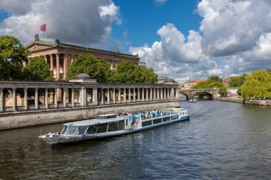 Berlin, 26.05.2025 Berlin 'deki River Spree' de bir tur teknesi. Berlin 'deki Müze Adası' ndan geçen turistlerle birlikte klasik mimari ve dramatik bulutlarla dolu bir nehir gezisi.