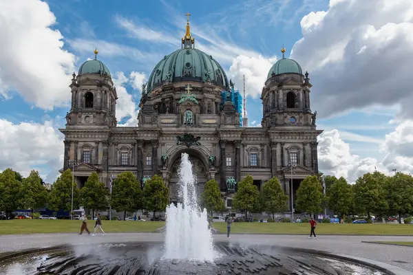 Almanya, Berlin, 26.05.2025, Çeşme ve Turistlerle Berlin Katedrali. Berlin Katedrali manzarası, etkileyici kubbeleri, merkezi bir çeşmesi ve ön planda yürüyen ziyaretçileri olan Berliner Dom..