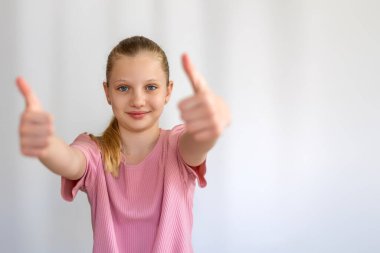 Kendine güvenen kız, iki parmağını kaldırıyor. Gülümseyen genç bir kız iki başparmağını uzatarak onay, güven ya da olumlu geri bildirim verir. Metin için boşluk