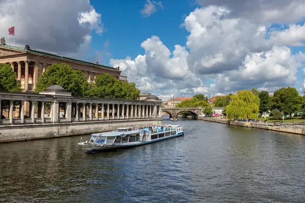 Almanya, Berlin, 26.05.2025 tarihi Berlin 'de nehir turu. Berlin 'deki Spree Nehri boyunca tarihi mimari, bereketli ağaçlar ve dramatik bulutlarla çevrili gezici bir tekne yol alıyor.