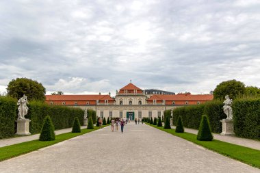 Lower Belvedere, Viyana, Ağustos 01, 2025. Viyana 'da bahçe heykelleri olan Aşağı Belvedere Sarayı. Avusturya, Viyana 'da Aşağı Belvedere manzarası, simetrik çitler, klasik heykeller ve çakıl yolu boyunca yürüyen ziyaretçiler.
