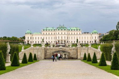 Belvedere Sarayı, Viyana, Avusturya - 01 Ağustos, 2025. Heykelleri ve fıskiyesi olan Yukarı Belvedere Sarayı. Viennas Yukarı Belvedere Sarayı 'nın barok heykelleri, dekoratif bir çeşmesi, budanmış çalıları ve yürüyen ziyaretçileri olan yakın görüntüsü..