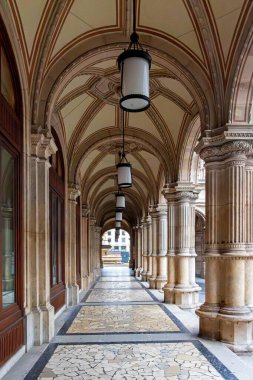 Kemerli koridorda sütunlar ve asılı fenerler var. Kubbeli tavanları, taş sütunları, mozaik döşemeleri ve tarihi bir Avrupa binasının parçası olan klasik fenerleri olan zarif bir koridor.