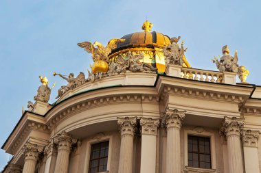 Hofburg Sarayı, Viyana, Avusturya - 01 Ağustos, 2025. Hofburg Sarayı 'nın altın kubbesi, gün batımında, Viyana. Avusturya 'nın Viyana kentindeki Hofburg Sarayı' nın tepesindeki yaldızlı kubbenin yakın görüntüsü ve özenle hazırlanmış heykeller sıcak günbatımı ışığında yıkandı..