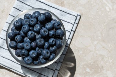 Havlunun üstünde bir kasede mavi böğürtlen