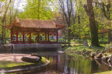 Güneşli bir günde, yeşil bir parkta, deniz kenarında Japon çardağı.
