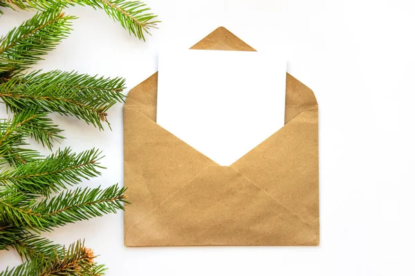 Ladin dallı minimalist kartpostal düzeni. Kraft zarfı, düz döşeme, üst manzara, yakın çekim. Noel, bayram ayrıntıları, dekorasyon, hediyeler, ambalaj, yeni yıl atmosferi..