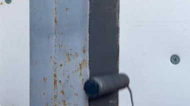 Mavi eldivenli bir solak metal kolonları silindirle boyar. Tamir ve inşaat kavramı. İnşaat malzemeleri ve aletleri. Demir için özel korozyon önleyici boya..