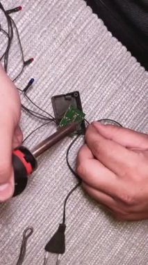 Bir adamın elleri tamir için lehim yapıyor. Lehim, uca odaklan. Bir adamın elinde lehim demiri. Elektrikli lehimleme demiriyle bir adamın ellerine yakın çekim. Bir tamirci lehimler Bir rölede