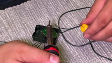 Bir adamın elinde lehim demiri. Ev aletlerini tamir etmede usta elektrikçi..