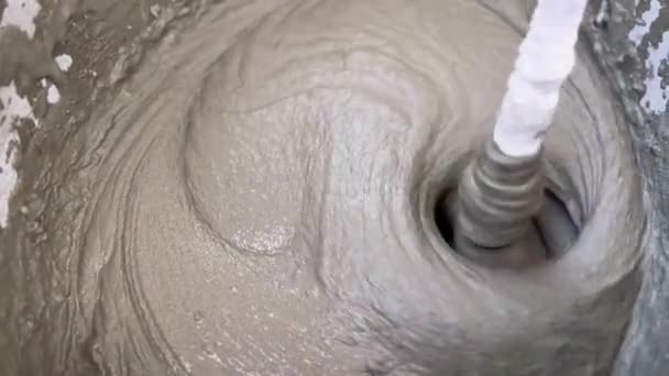 将水泥胶粘剂与搅拌机在桶内密闭 混合砂浆的质地混合在一起 配制施工混合料 建筑业体力劳动自动化的概念 — 图库视频影像