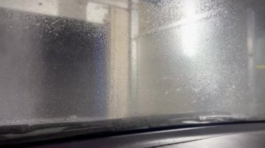 Ön camdan kayan köpük. Araba kabininden köpükle otomatik araba ön cam yıkama görüntüsü. Araba kulübesinden otomatik oto yıkama manzarası. İçeriden görüntüle.