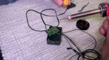 Bir adamın elinde lehim demiri. Evdeki elektrikli aletleri tamir etmek için lehim makinesi kullanan bir adam. Noel ağacı çelengi tamiri. Lehim demiriyle teneke alıyor ve mikro devreye koyuyor..
