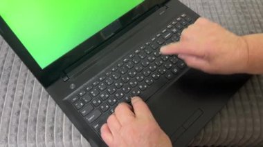 Yeşil ekranda dizüstü bilgisayar kullanan yaşlı bir kadının elleri. Bir emekli dizüstü bilgisayarda çalışmayı öğrenir. Yeşil ekran kromatonlu dizüstü bilgisayar ve dolgun kadın elleri. Olgun kadın elleri yavaşça