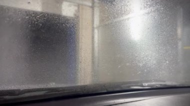Araba kabininden köpük otomatik oto yıkama manzaralı otomatik araba ön cam yıkama görüntüsü. Ön camdan kayan köpük. İçeriden bak. Arabayı yıkama zamanı..