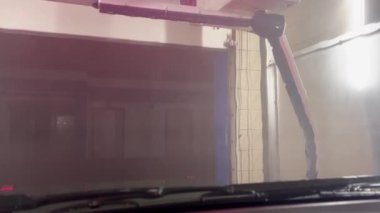 Robot oto yıkama, otomatik yıkama sistemi. Araba yıkamada bir arabayı sabunlarken çekilmiş renkli kısa bir video. Sabun solüsyonu. Araba camında beyaz köpük deterjanı var..