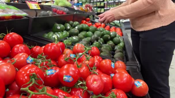 ミッサウガ カナダ スーパーマーケットの野菜販売部門 スーパーマーケットのクローズアップで枝の上の新鮮なトマト 白人女性 アボカド — ストック動画