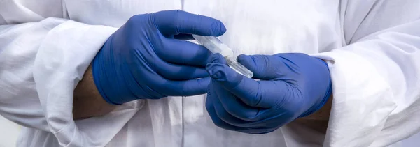 Hands in blue gloves with a syringe. Blue latex gloves for protection. Doctor in blue gloves close up.