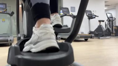 19.10.23 - Mississauga, Kanada. Spor salonundaki bir kadın spor makinesine biniyor. GYM, Matrix . Kardiyo yüklendi. Çiçekli kadın bacaklarının dikiz görüntüsü. Sağlıklı yaşam tarzı kavramı.