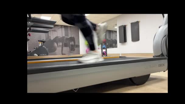 カナダのミシサガ Gymについて ジムで走る トレッドミルで女性の足を走らせるのサイドビュー トレッドミルで走っている女性の脚のビデオ — ストック動画