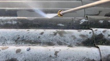 Yüksek basınçlı temizleyici ile çatı temizliği. Su basıncına yakın çekim, toprağı temizliyor. Geçmişe sünger çekmek için ideal bir çözüm..