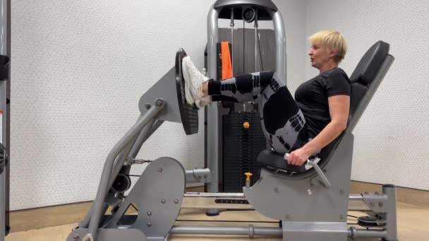 프레스 Hamstring 훈련의 비디오 체육관에서 시뮬레이터에 의도적인 기계에 여성의 클로즈업 — 비디오