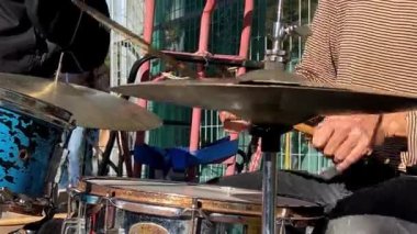 Güneş ışığı, enerjik bir şekilde titreyen, yıpranmış bir davula vurarak şehir hayatının nabzını yankılıyor. Kavram: Farklı şehir manzaralarını birbirine bağlayan şehir ritimleri.