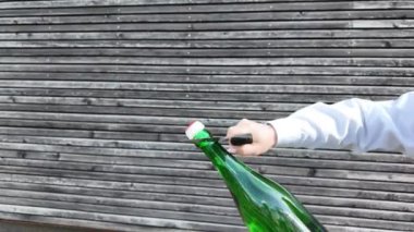 Şarabı tutan ve açan kişi. Şampanya kılıcı. Bir insan yeşil şarap şişesinin nasıl açılacağını gösteriyor. Bu işlem folyoyu çıkarmayı, tirbuşonu takmayı ve dikkatlice yerleştirmeyi içeriyor.