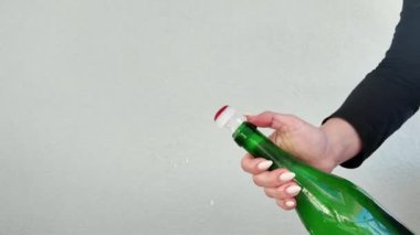 Şampanya şişesinin açılışı. Bir insan elinde bir şişe şarap tutarken gösteriliyor, etiketini ve tasarımını sergiliyor. Şişe sıkıca tutularak dik tutuluyor. Ayarlar tarafsız.
