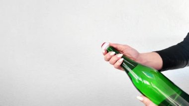 Elinde bir şişe şarap tutan bir kadın görülüyor. Etikete bakıyor ve şişeyi yakından inceliyor..