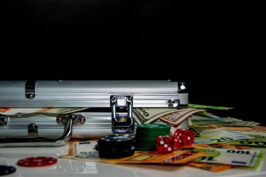 A silver aluminum case sits on a table with stacks of cash and poker chips. clipart