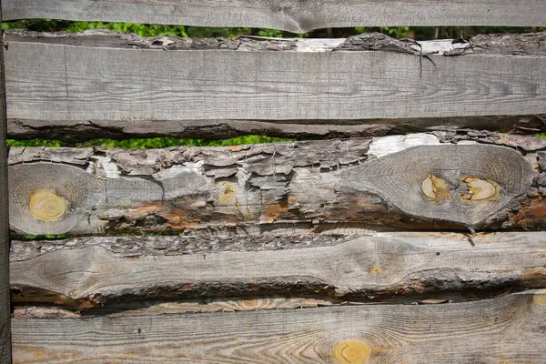 stock image A close-up image of a wooden fence constructed with multiple layers of logs. The wood is weathered and worn, showcasing its natural textures and patterns.